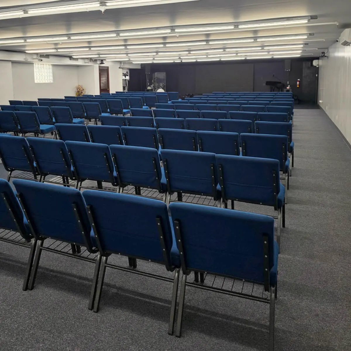 El salón de la masterclass en Brooklyn: filas de sillas azules acolchadas y el escenario al fondo